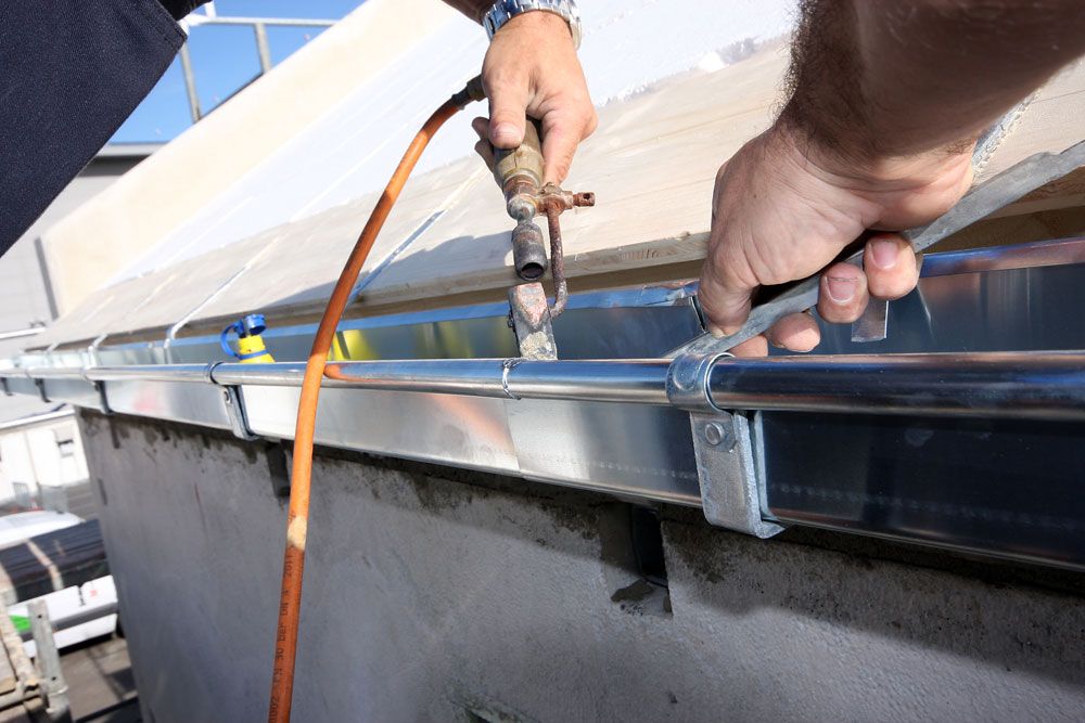 Ein Handwerker repariert eine Dachrinne